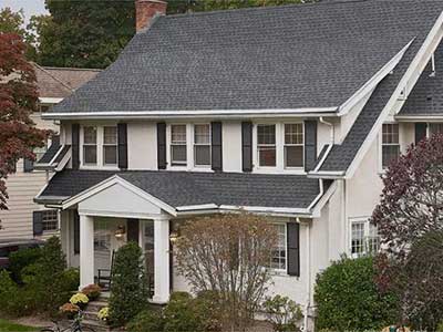 Front view of a white mid-class, two-story home with dark gray GAF asphalt shingles on its roof