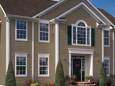 Front view of a higher-end, two-story home with light brown CertainTeed siding