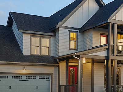 Front view of a white mid-class, two-story home at dusk with Mastic siding